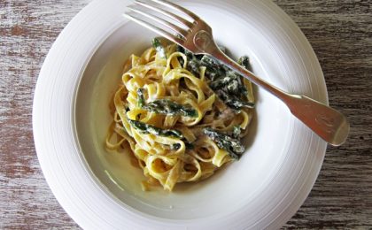 Fondina_bianca_contiene_fettuccine_condite_asparagi_forchetta_appoggiata-sul_piatto